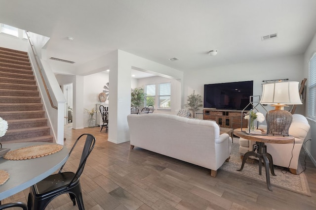 living room featuring stairway, visible vents, and light wood-type flooring