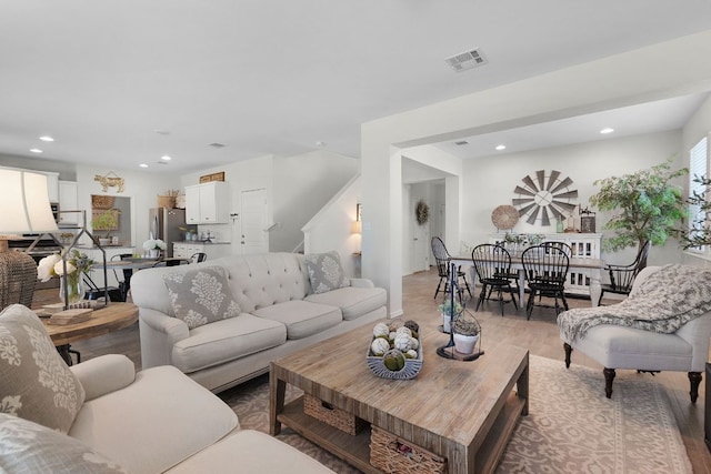living area featuring stairway, light wood finished floors, visible vents, and recessed lighting
