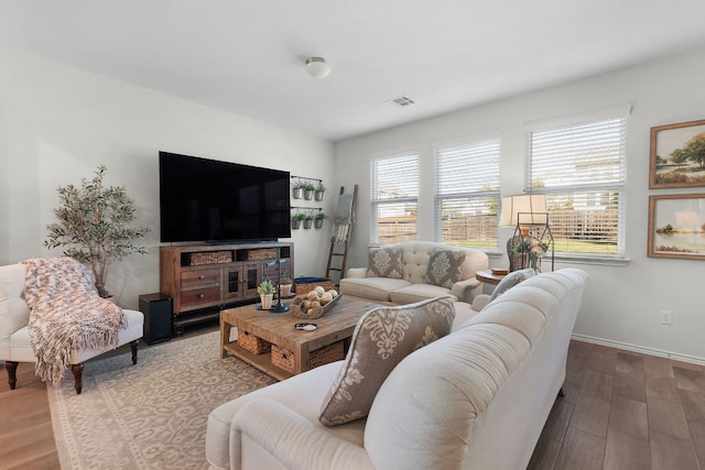 living area with visible vents, baseboards, and wood finished floors
