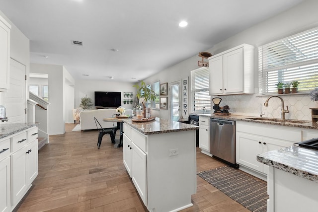 kitchen featuring white cabinetry, backsplash, visible vents, stainless steel dishwasher, and a sink