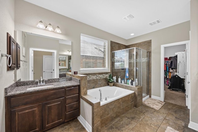 full bath with a bath, a shower stall, vanity, a walk in closet, and baseboards