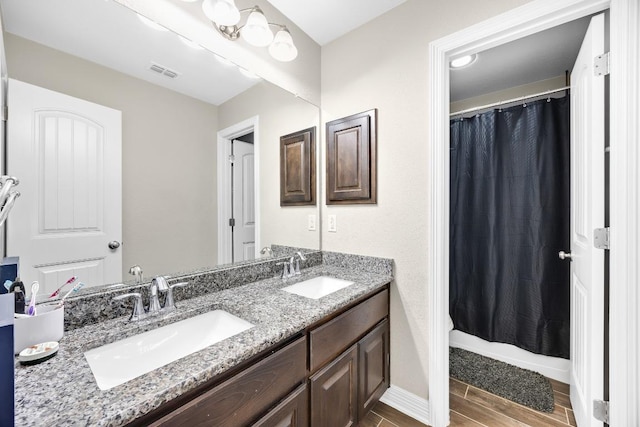 bathroom featuring double vanity, wood finished floors, and baseboards