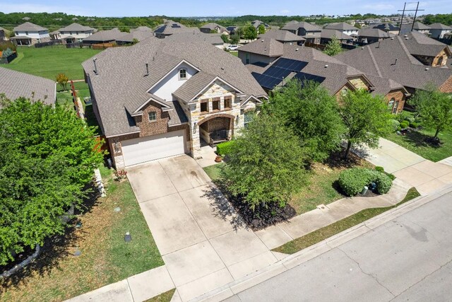 view of front facade with stone siding, driveway, a residential view, and an attached garage