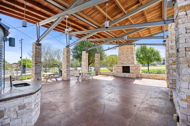 view of patio / terrace featuring ceiling fan and an outdoor stone fireplace