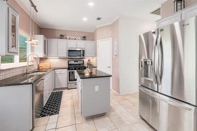 2204 Rick Whinery Dr, Austin, TX 78728 - kitchen with stainless steel appliances, a kitchen island, decorative backsplash, ornamental molding, and dark stone countertops