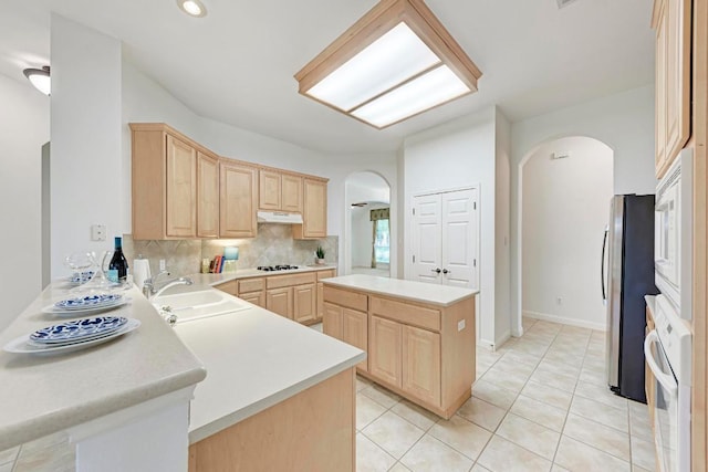 2709 Quiet Moon Trl, Cedar Park, TX 78613 - kitchen with light brown cabinetry, arched walkways, white appliances, a sink, and light countertops