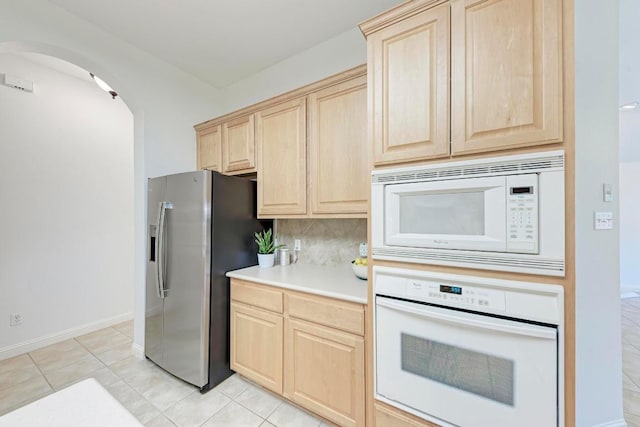2709 Quiet Moon Trl, Cedar Park, TX 78613 - kitchen featuring white appliances, light brown cabinetry, arched walkways, and tasteful backsplash