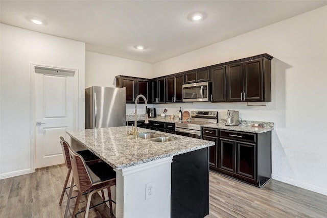 14209 Jeannette Rankin Rd, Manor, TX 78653 - kitchen with appliances with stainless steel finishes, a sink, light wood finished floors, baseboards, and an island with sink