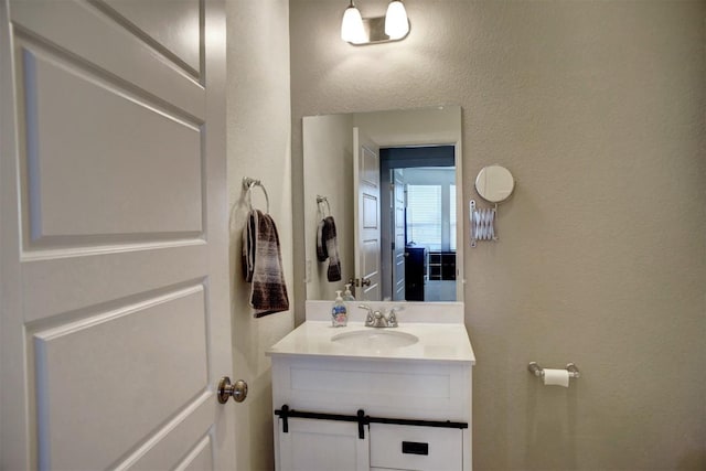 half bath with a textured wall and vanity