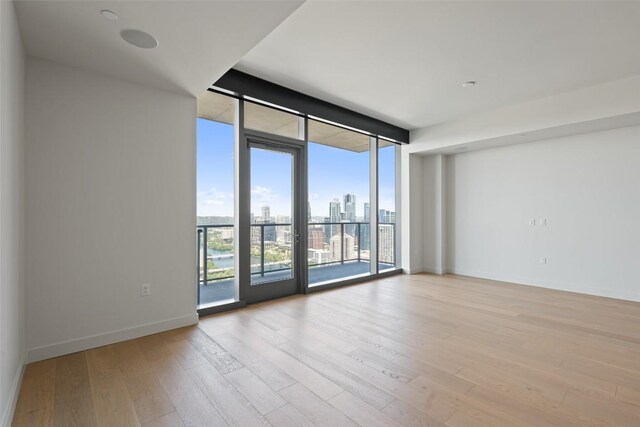 44 E Ave Unit 4302, Austin, TX 78701 - unfurnished room featuring a wall of windows, a skyline view, and wood finished floors