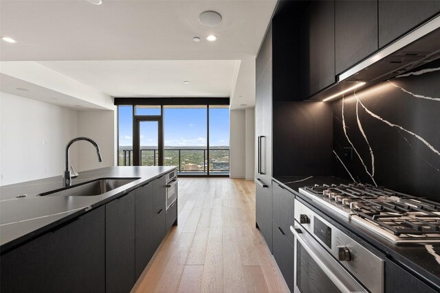 44 E Ave Unit 4302, Austin, TX 78701 - kitchen with modern cabinets, dark cabinetry, stainless steel appliances, light wood-style flooring, and a wall of windows