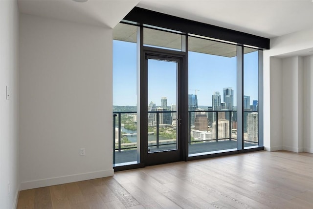 44 E Ave Unit 4302, Austin, TX 78701 - empty room featuring expansive windows, wood finished floors, a view of skyline, and a water view