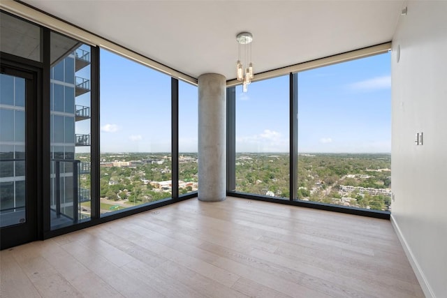 44 E Ave Unit 2307, Austin, TX 78701 - spare room with expansive windows, wood finished floors, a chandelier, and baseboards