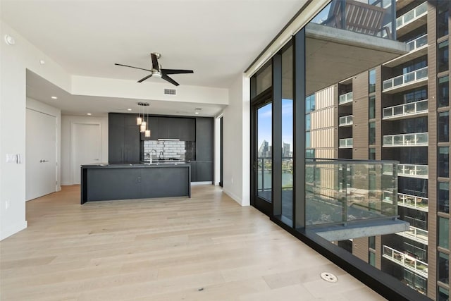 44 E Ave Unit 2307, Austin, TX 78701 - kitchen featuring ceiling fan, pendant lighting, decorative backsplash, dark countertops, and light wood finished floors