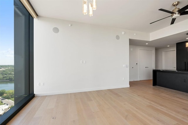 44 E Ave Unit 2307, Austin, TX 78701 - unfurnished living room with light wood finished floors, ceiling fan, baseboards, and a chandelier
