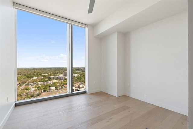 44 E Ave Unit 2307, Austin, TX 78701 - empty room with wood finished floors, healthy amount of natural light, a wall of windows, and baseboards