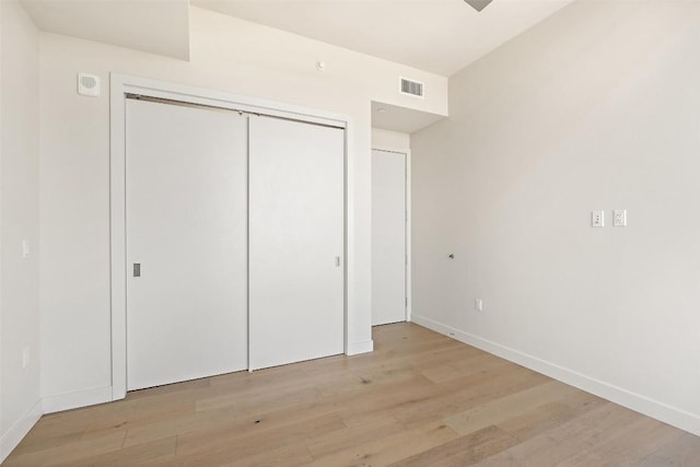 44 E Ave Unit 2307, Austin, TX 78701 - unfurnished bedroom with light wood-type flooring, baseboards, and a closet