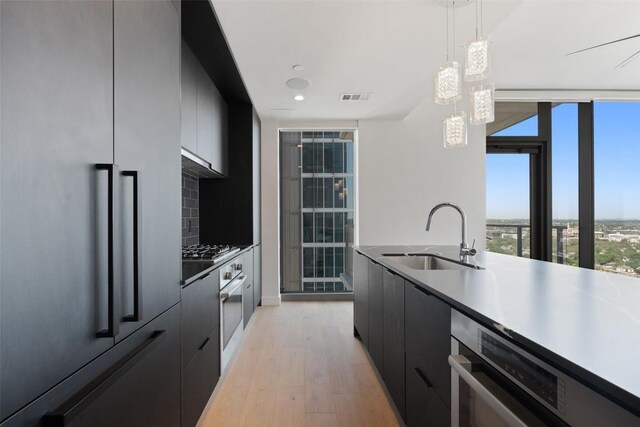 44 E Ave Unit 2307, Austin, TX 78701 - kitchen with paneled built in fridge, a sink, modern cabinets, light wood-style flooring, and dark cabinetry