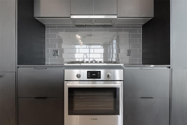 44 E Ave Unit 2307, Austin, TX 78701 - kitchen with wall oven, modern cabinets, backsplash, and range hood