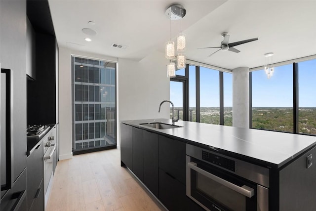 44 E Ave Unit 2307, Austin, TX 78701 - kitchen featuring a sink, dark cabinetry, appliances with stainless steel finishes, modern cabinets, and light wood finished floors