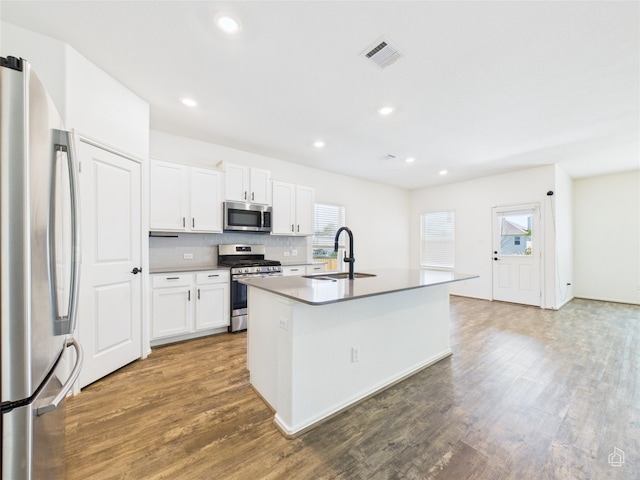 3113 Windy Vane Dr, Pflugerville, TX 78660 - kitchen with stainless steel appliances, a sink, wood finished floors, decorative backsplash, and a center island with sink