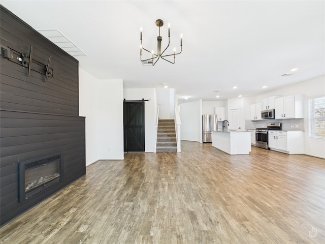 3113 Windy Vane Dr, Pflugerville, TX 78660 - unfurnished living room with a sink, light wood-style flooring, a chandelier, a barn door, and a fireplace