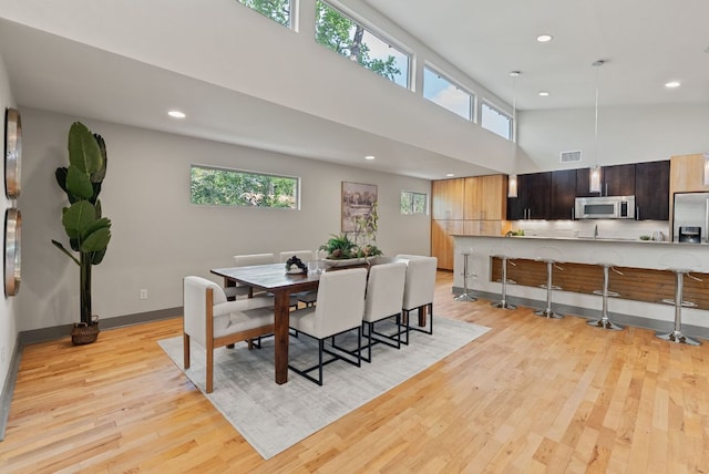 5607 Jim Hogg Ave, Austin, TX 78756 - dining area featuring recessed lighting, light wood-style flooring, a towering ceiling, and baseboards