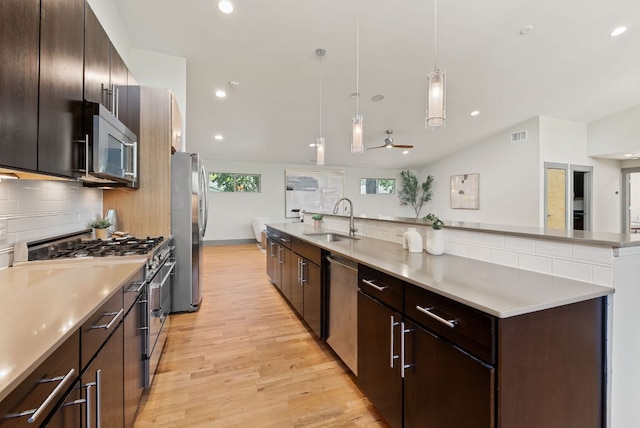 5607 Jim Hogg Ave, Austin, TX 78756 - kitchen featuring appliances with stainless steel finishes, a sink, light wood-style floors, backsplash, and a large island