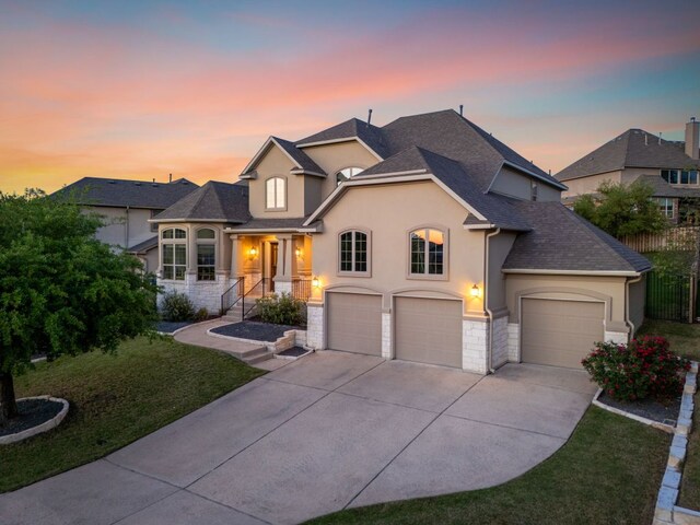 17012 Rush Pea Cir, Austin, TX 78738 - french country home featuring stucco siding, concrete driveway, stone siding, roof with shingles, and an attached garage