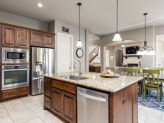 17012 Rush Pea Cir, Austin, TX 78738 - kitchen with stainless steel appliances, a sink, light tile patterned flooring, arched walkways, and light stone countertops