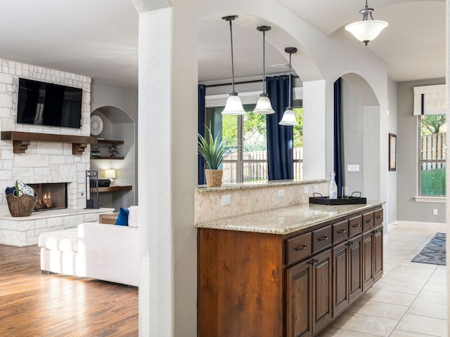17012 Rush Pea Cir, Austin, TX 78738 - kitchen featuring open floor plan, light stone countertops, a fireplace, and hanging light fixtures