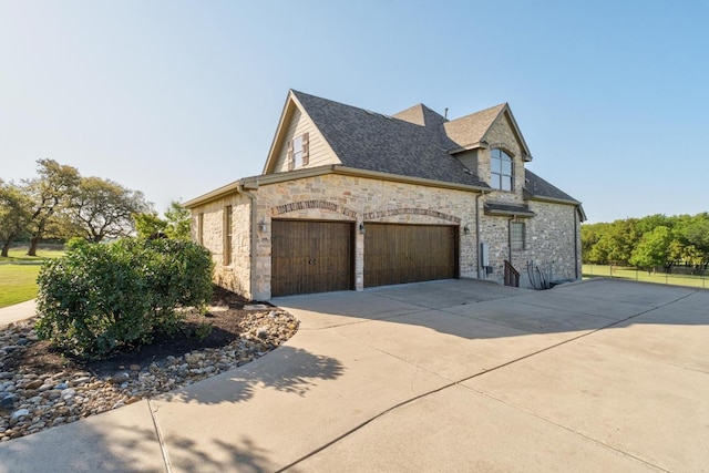 404 Oak Meadow Dr, Georgetown, TX 78628 - view of home's exterior with driveway, stone siding, an attached garage, and a shingled roof