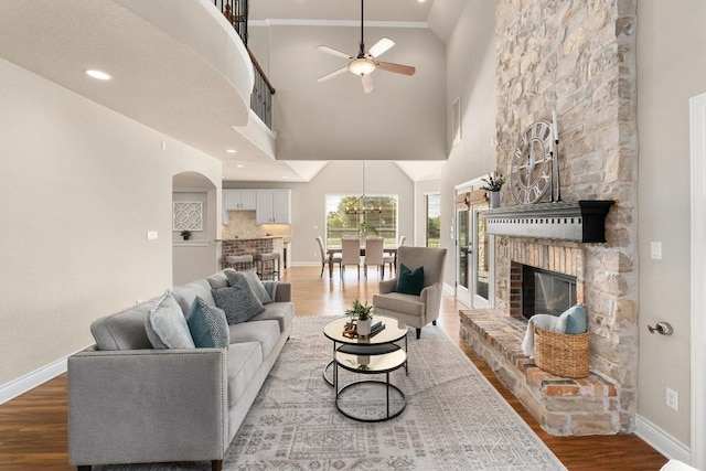 404 Oak Meadow Dr, Georgetown, TX 78628 - living area featuring wood finished floors, ceiling fan, high vaulted ceiling, a stone fireplace, and arched walkways