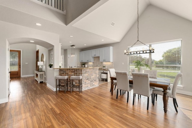 404 Oak Meadow Dr, Georgetown, TX 78628 - dining room featuring a chandelier, arched walkways, light wood-style floors, high vaulted ceiling, and recessed lighting