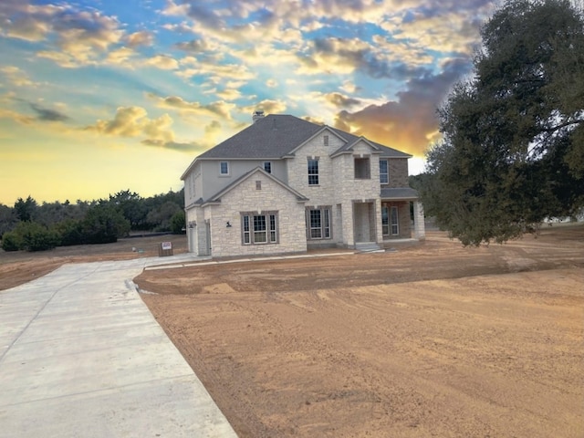 french country inspired facade featuring driveway and stone siding