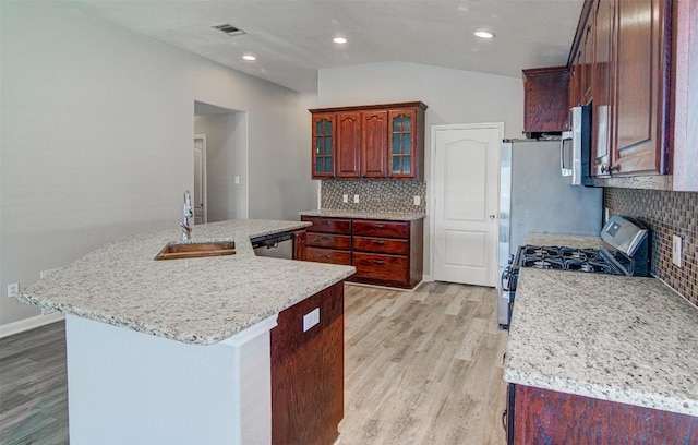 233 Devonshire Dr, Kyle, TX 78640 - kitchen featuring a sink, appliances with stainless steel finishes, lofted ceiling, light wood-type flooring, and decorative backsplash