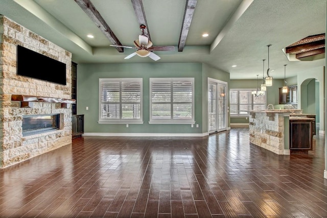 209 Aldea St, Georgetown, TX 78633 - unfurnished living room featuring ceiling fan, a stone fireplace, dark wood-style flooring, beamed ceiling, and recessed lighting