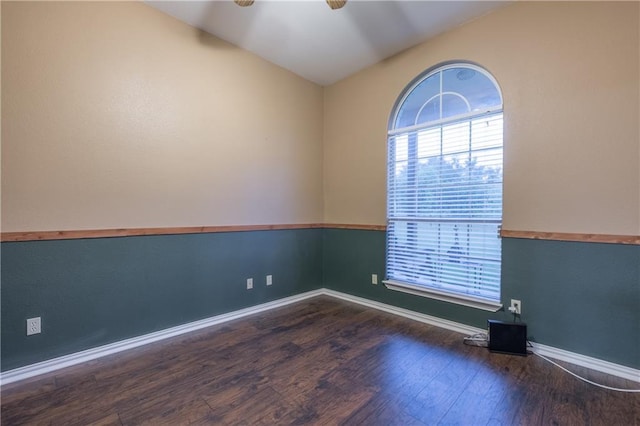 empty room with wood finished floors, baseboards, a ceiling fan, and vaulted ceiling