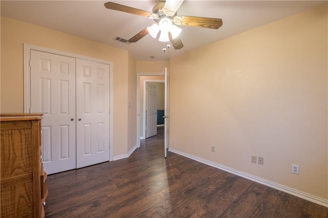 unfurnished bedroom with dark wood-style flooring, a closet, baseboards, visible vents, and ceiling fan
