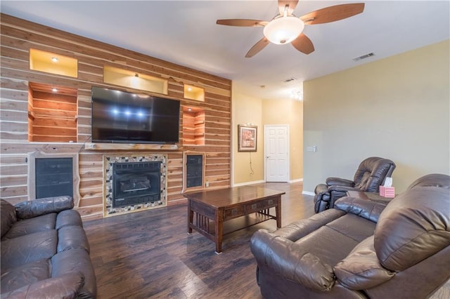 living area with baseboards, visible vents, ceiling fan, a tile fireplace, and wood finished floors