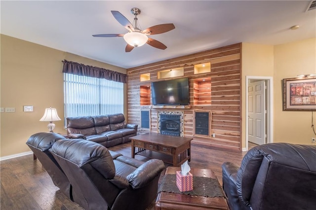 living area featuring wood finished floors, a fireplace, baseboards, and a ceiling fan
