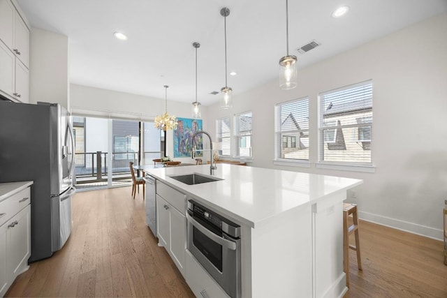 kitchen featuring visible vents, a sink, light wood-style floors, recessed lighting, and stainless steel appliances