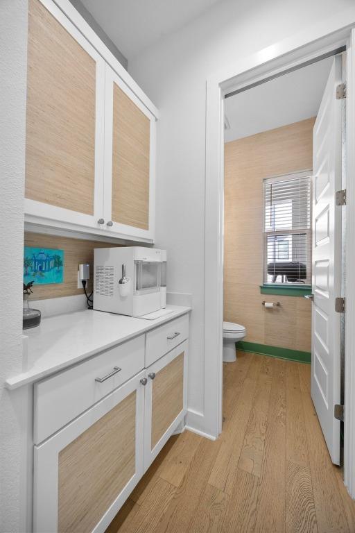 bathroom with baseboards, toilet, and wood finished floors