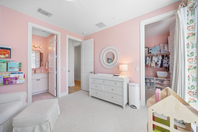 bedroom featuring ensuite bath, visible vents, and light colored carpet