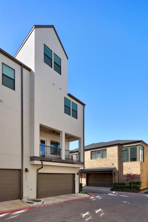 view of front facade featuring brick siding, an attached garage, a balcony, and stucco siding