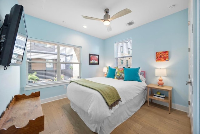 bedroom with visible vents, multiple windows, baseboards, and wood finished floors