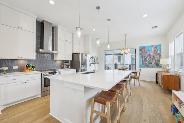 3901 Vantage Dr, Austin, TX 78731 - kitchen with appliances with stainless steel finishes, wall chimney range hood, backsplash, an island with sink, and light wood-style floors