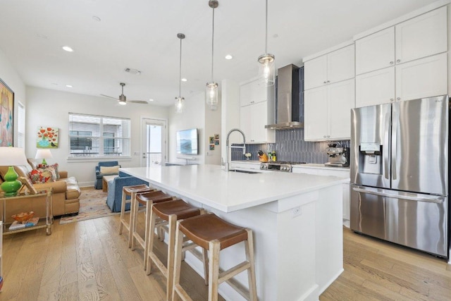 3901 Vantage Dr, Austin, TX 78731 - kitchen featuring stainless steel fridge with ice dispenser, wall chimney range hood, a sink, decorative backsplash, and light wood finished floors