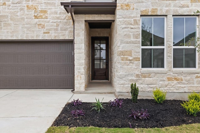 property entrance featuring a garage, driveway, and stone siding