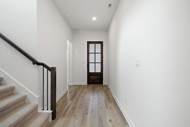 entrance foyer with stairway, visible vents, baseboards, and light wood finished floors